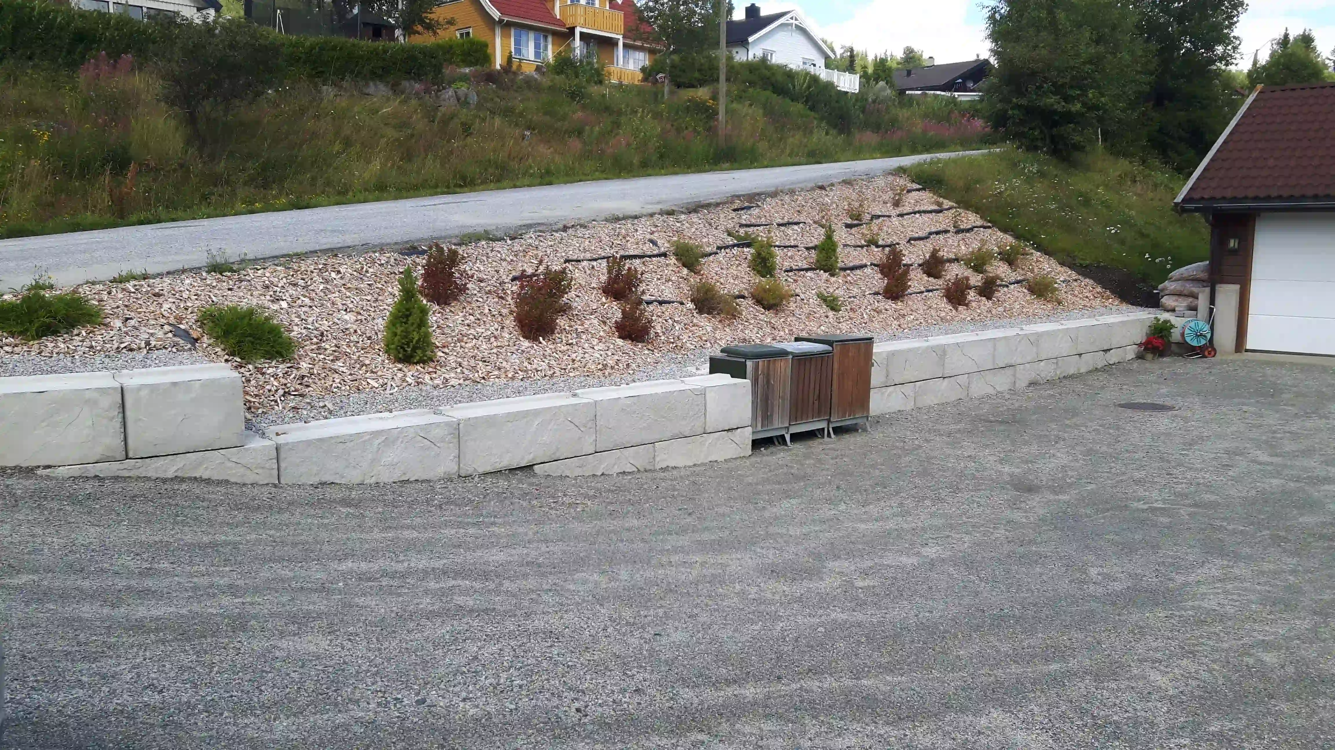 Støttemur nedenfor vei og beplantning i bakke